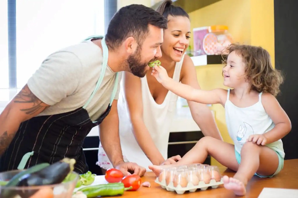woman-watching-daughter-feeding-bell-pepper-to-her-father